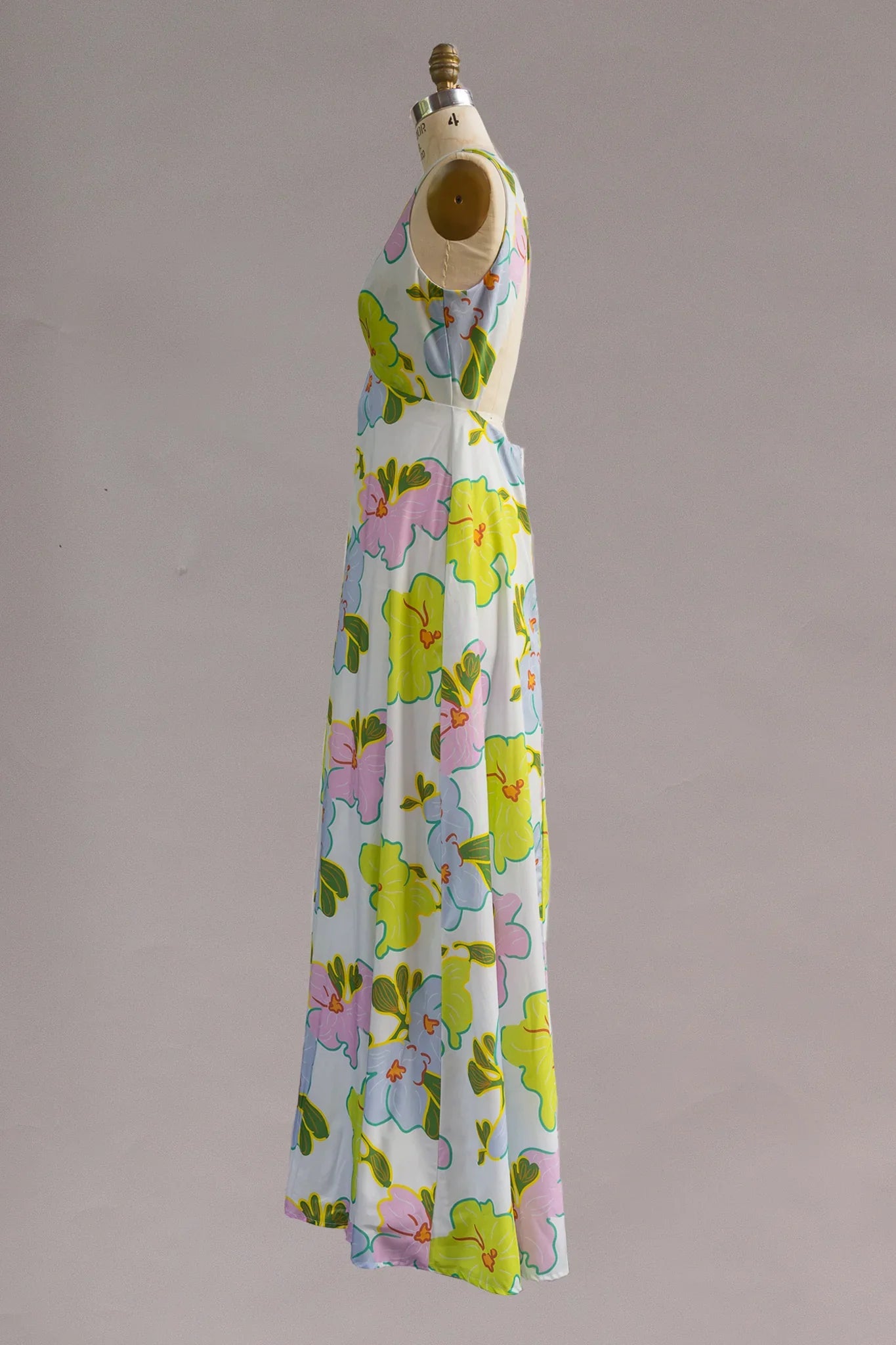 Sleeveless muumuu dress with large pastel Hawaiian floral print, shown on mannequin