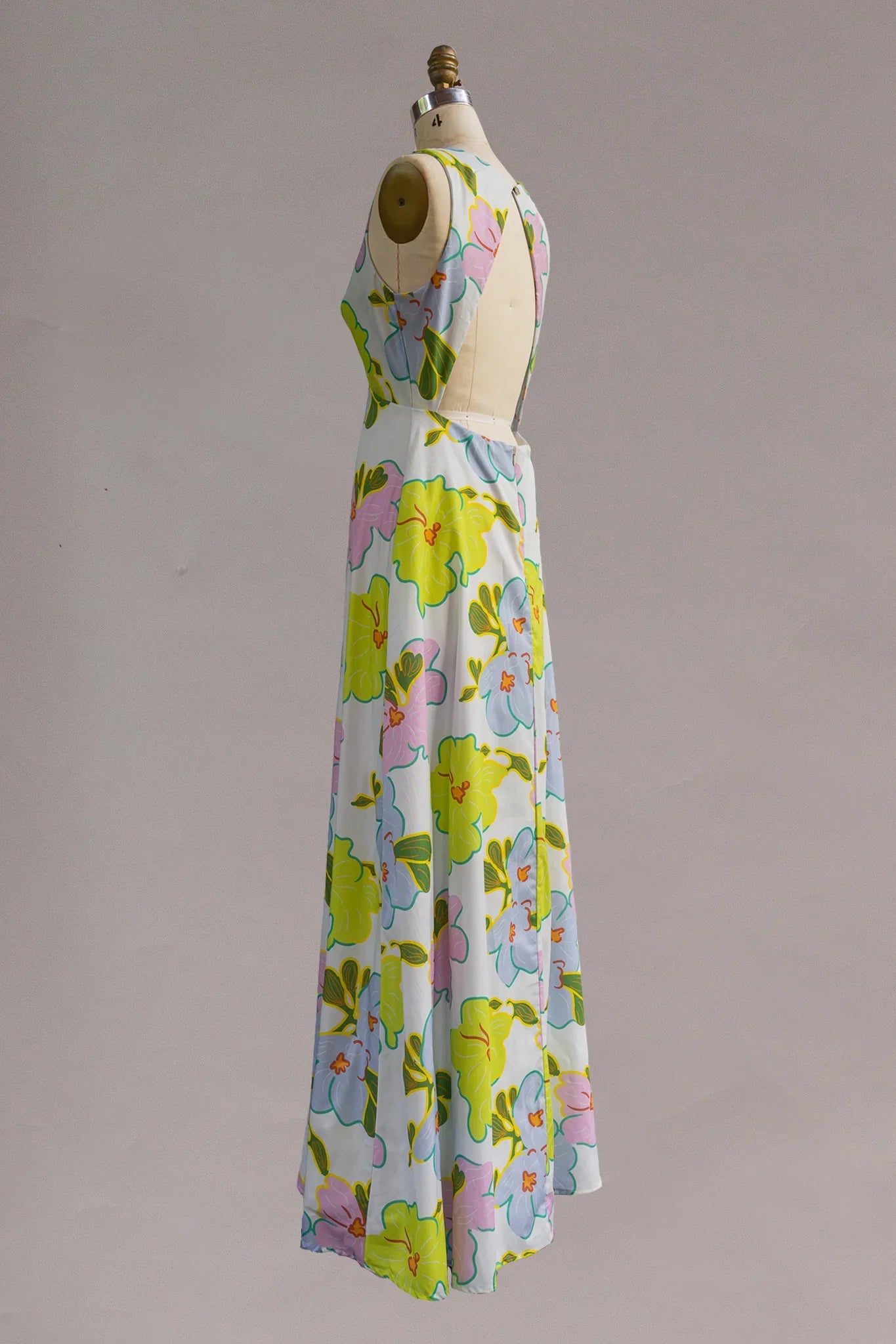 Sleeveless maxi dress with pastel Hawaiian floral print on mannequin, side view