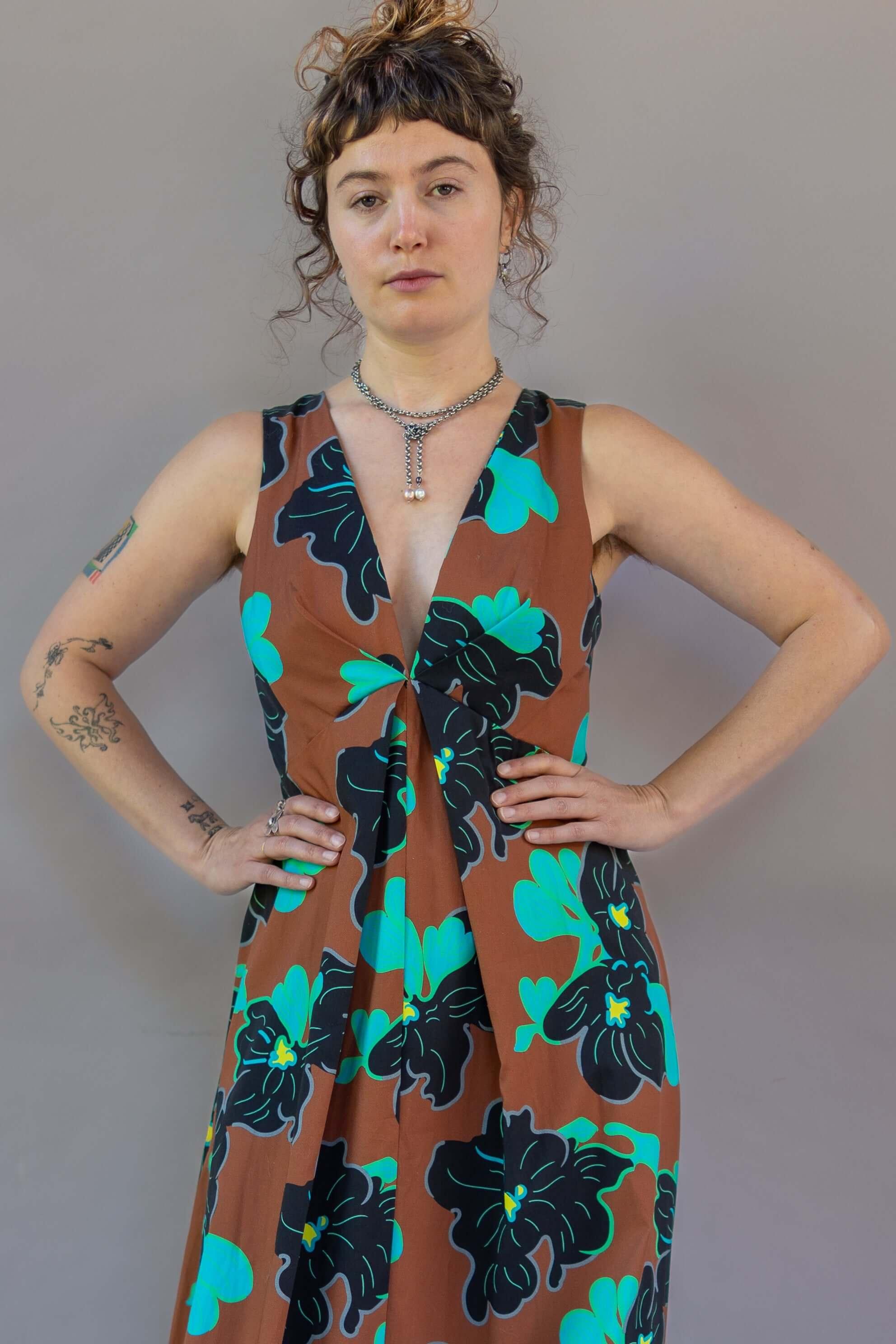 Model wearing Origami Dress 1961 Chestnut featuring brown fabric with teal floral pattern.