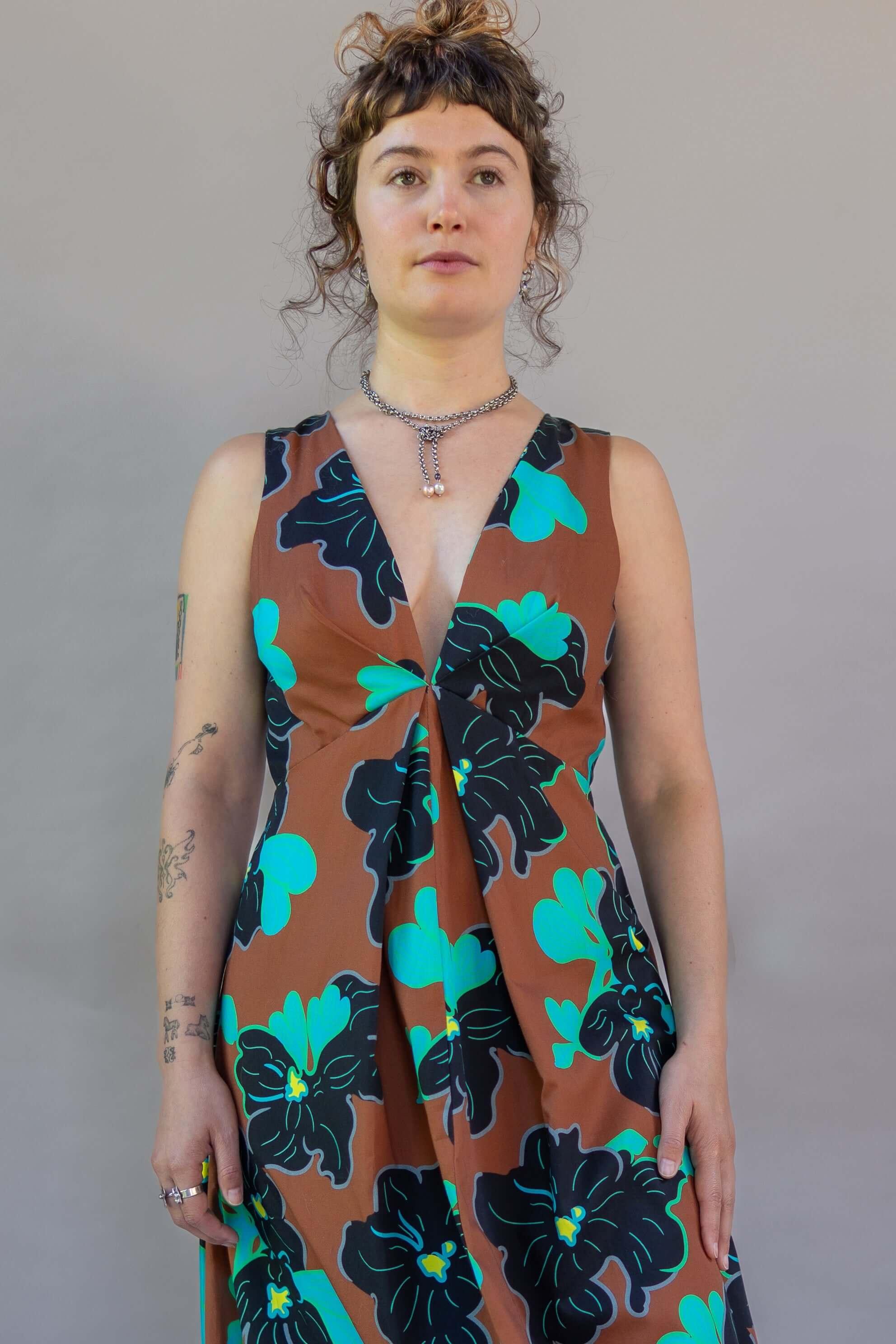 Model wearing Origami Dress 1961 Chestnut with a deep plunge and floral design.