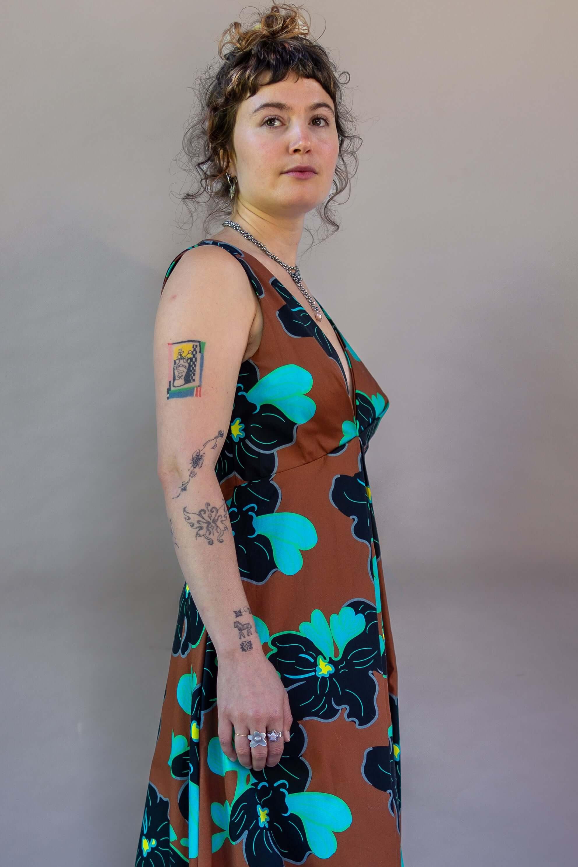 Model wearing Origami Dress 1961 Chestnut featuring vibrant floral print and plunging neckline.