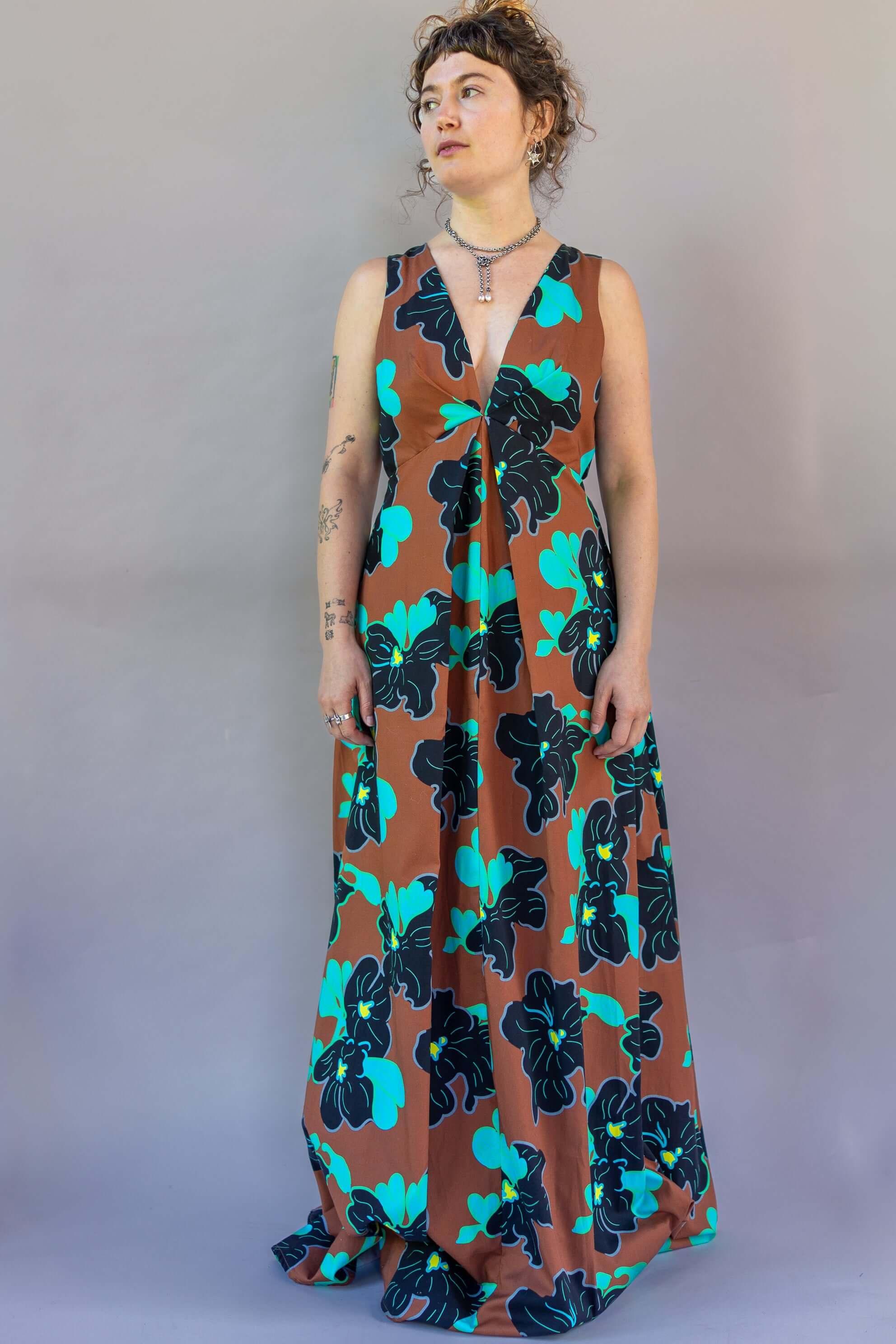 Origami Dress 1961 Chestnut displayed on a model, featuring a deep plunge neck and open back in vibrant floral pattern.