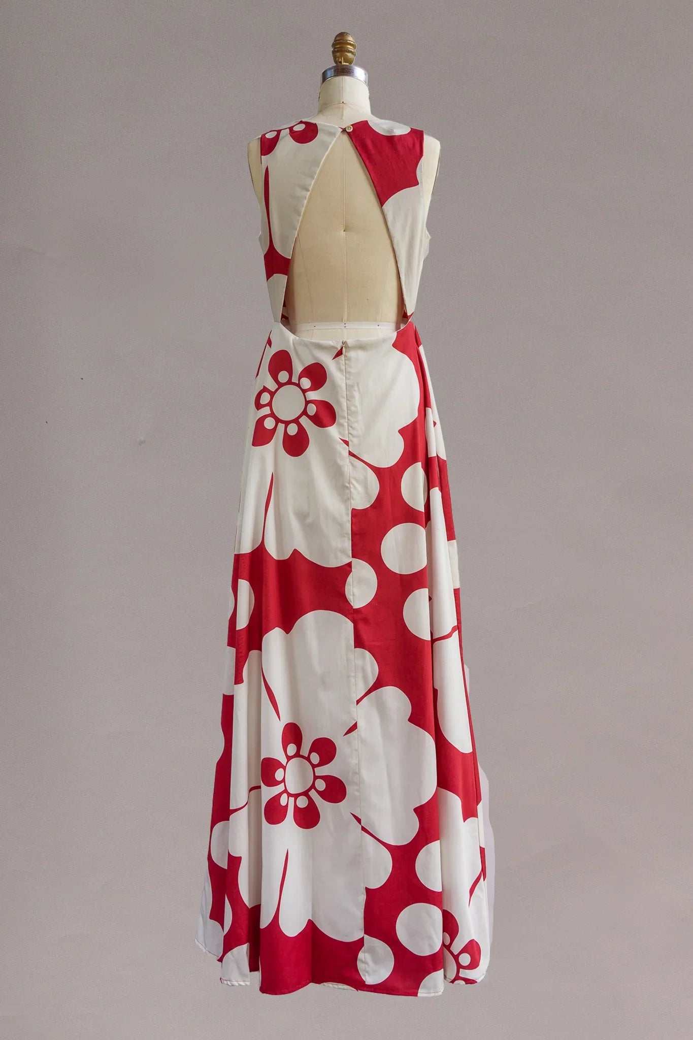 Back view of a sleeveless maxi dress with bold red and white floral print and open back design