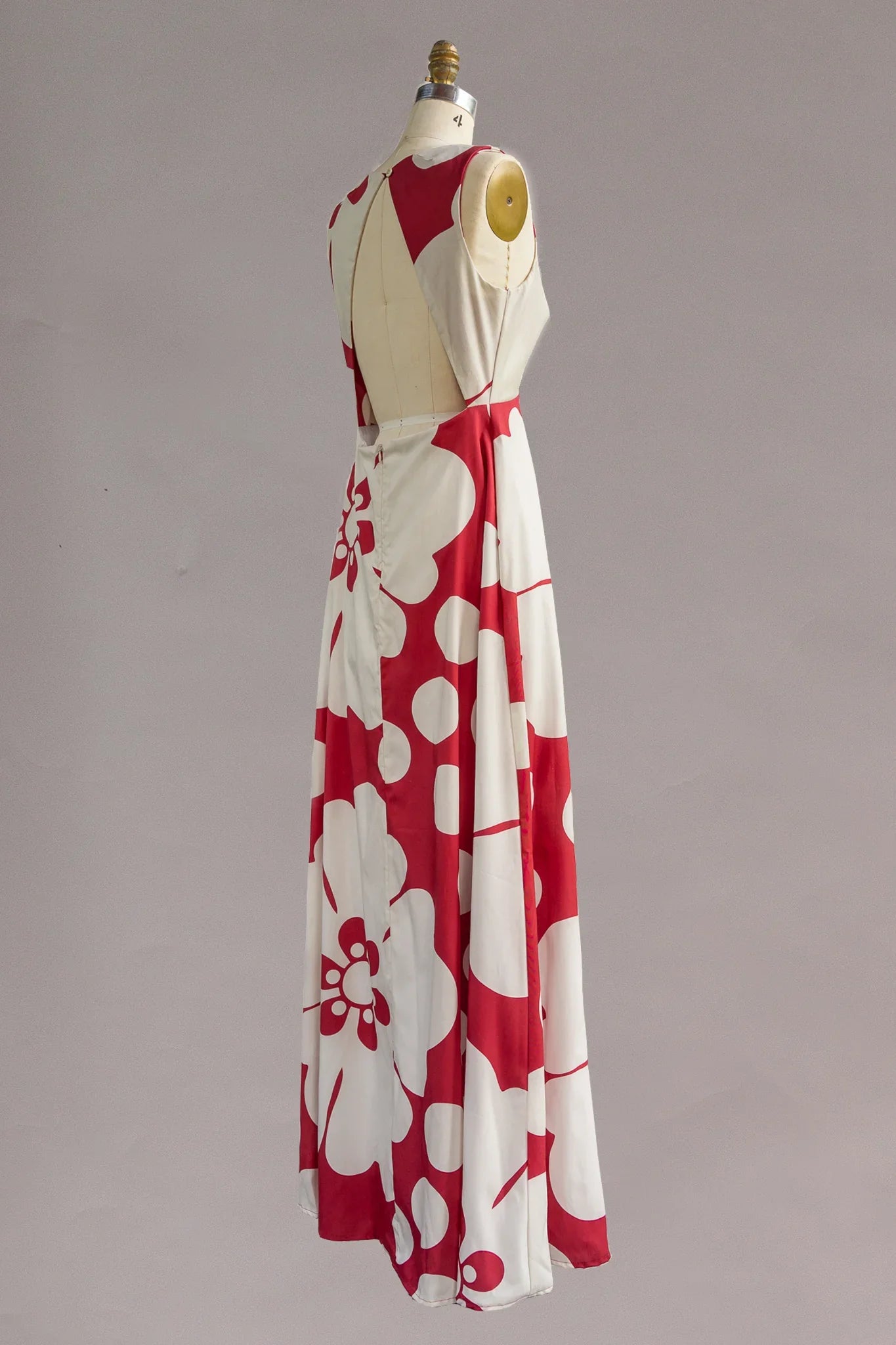 Red and white maxi dress with bold Hawaiian floral print, sleeveless, on dress form