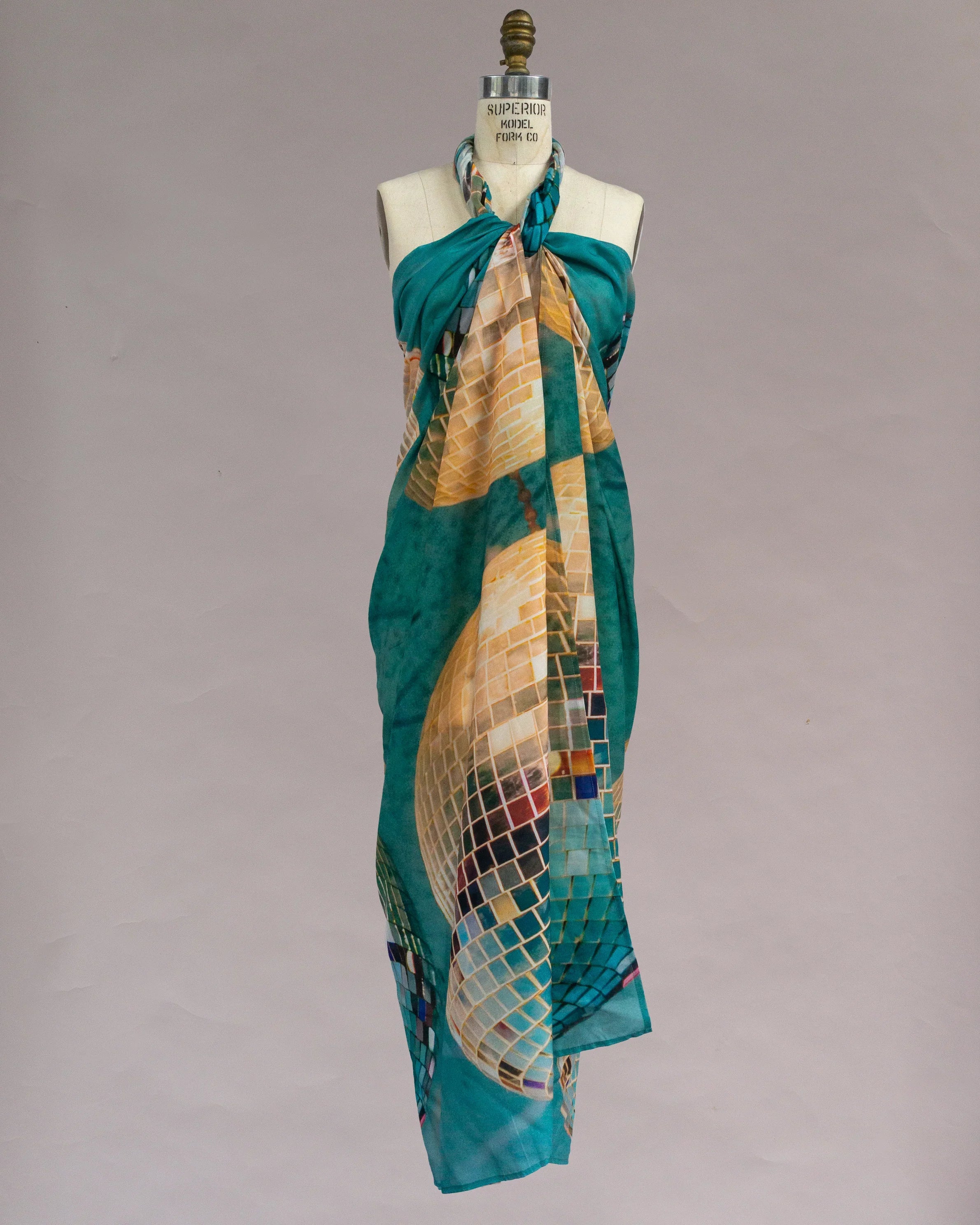 Teal pareo with abstract mosaic print displayed on a dress form against a neutral background