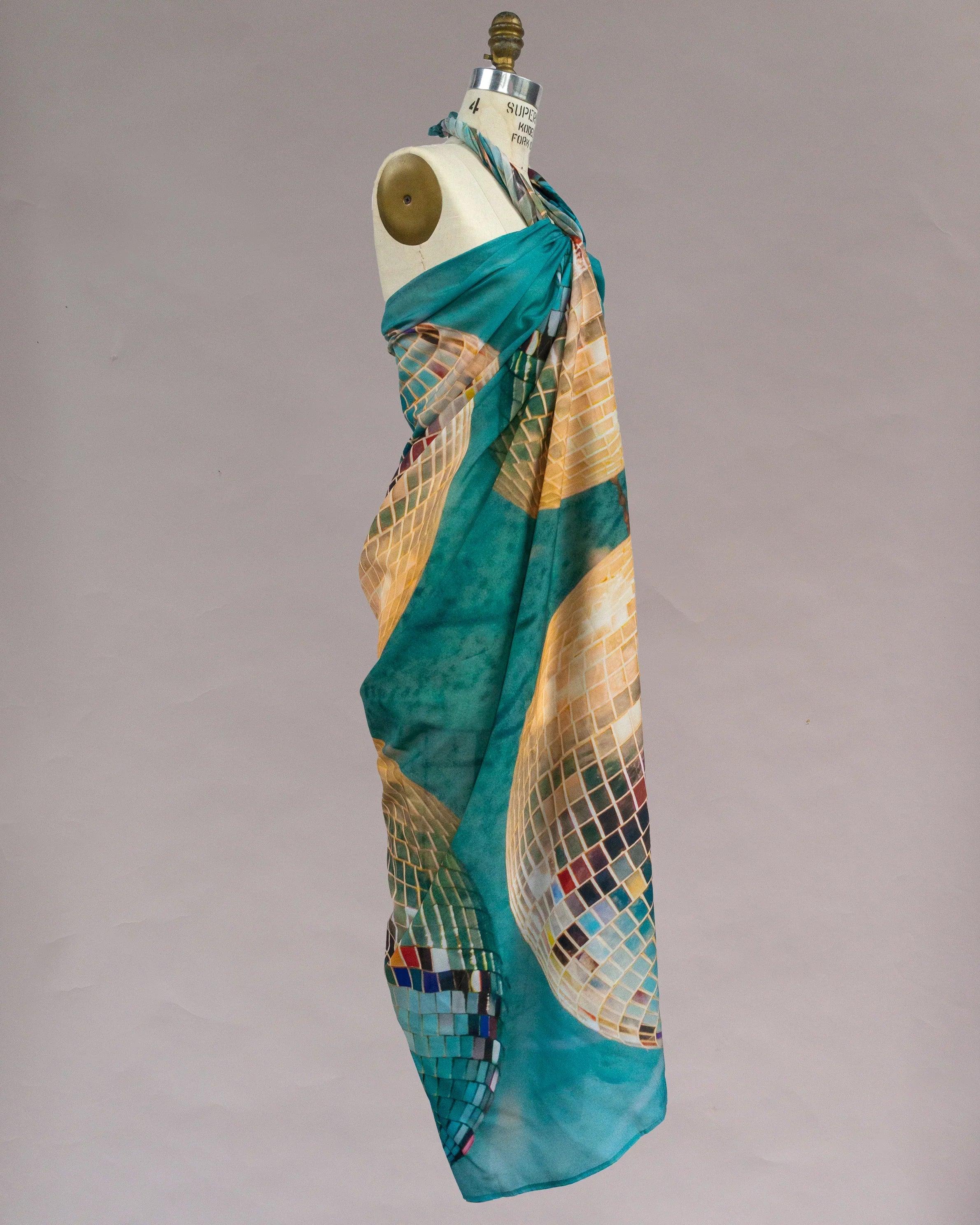Teal pareo with gold and multicolor disco ball print draped on a dress form