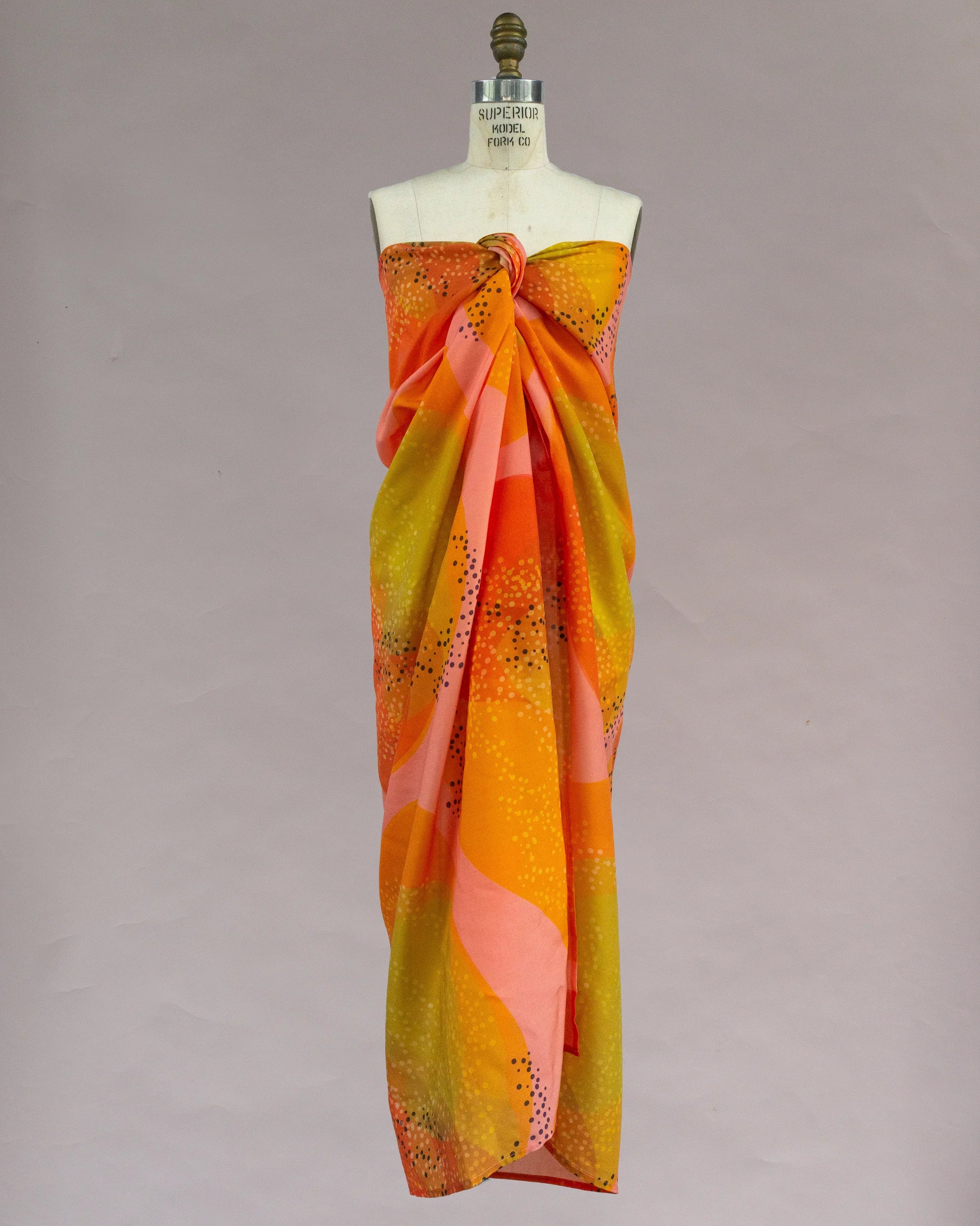 Colorful pareo wrap with orange, yellow, and pink abstract Hawaiian print on mannequin