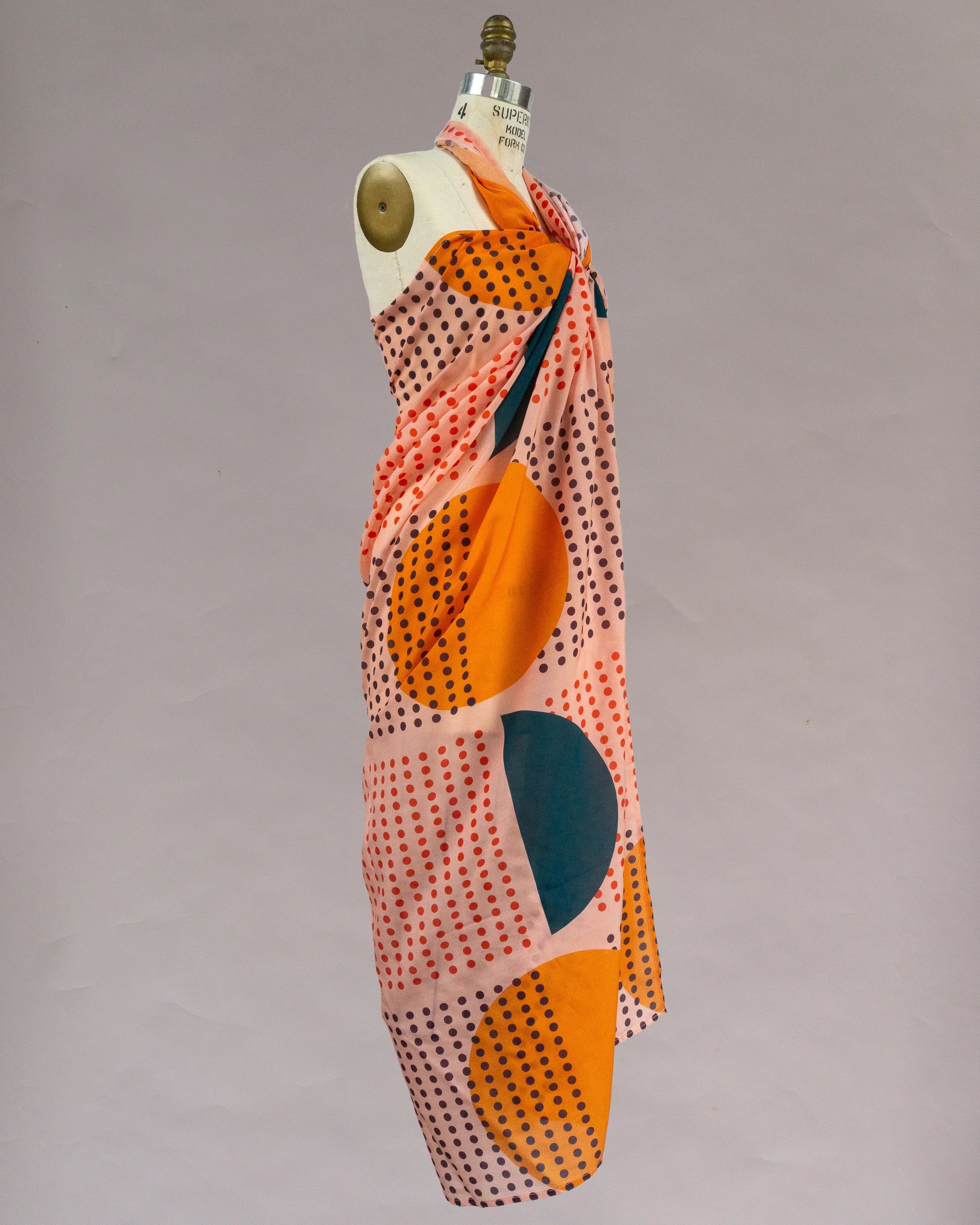 Colorful pareo with sunrise-inspired geometric dot print draped on mannequin