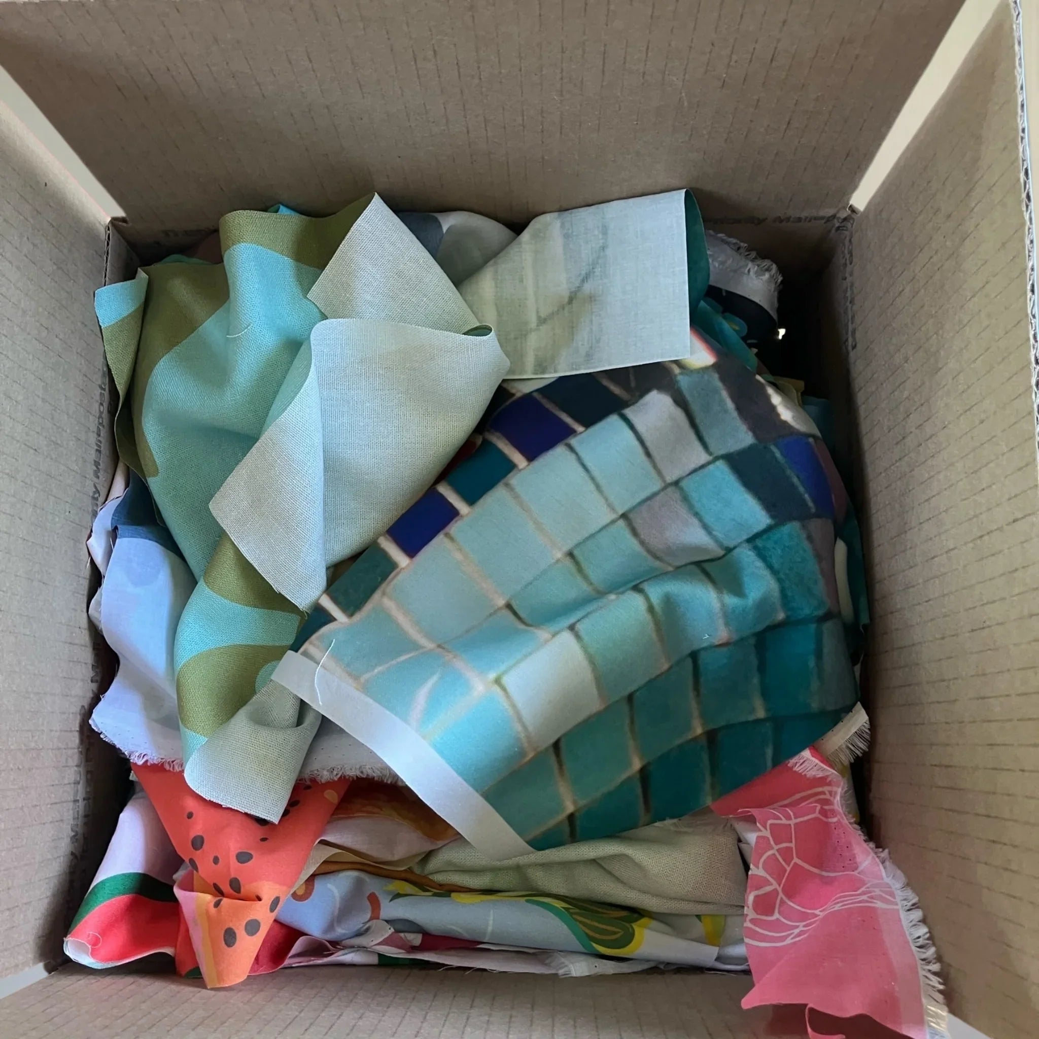 Box of colorful Hawaiian print fabric scraps for quilting or sewing projects