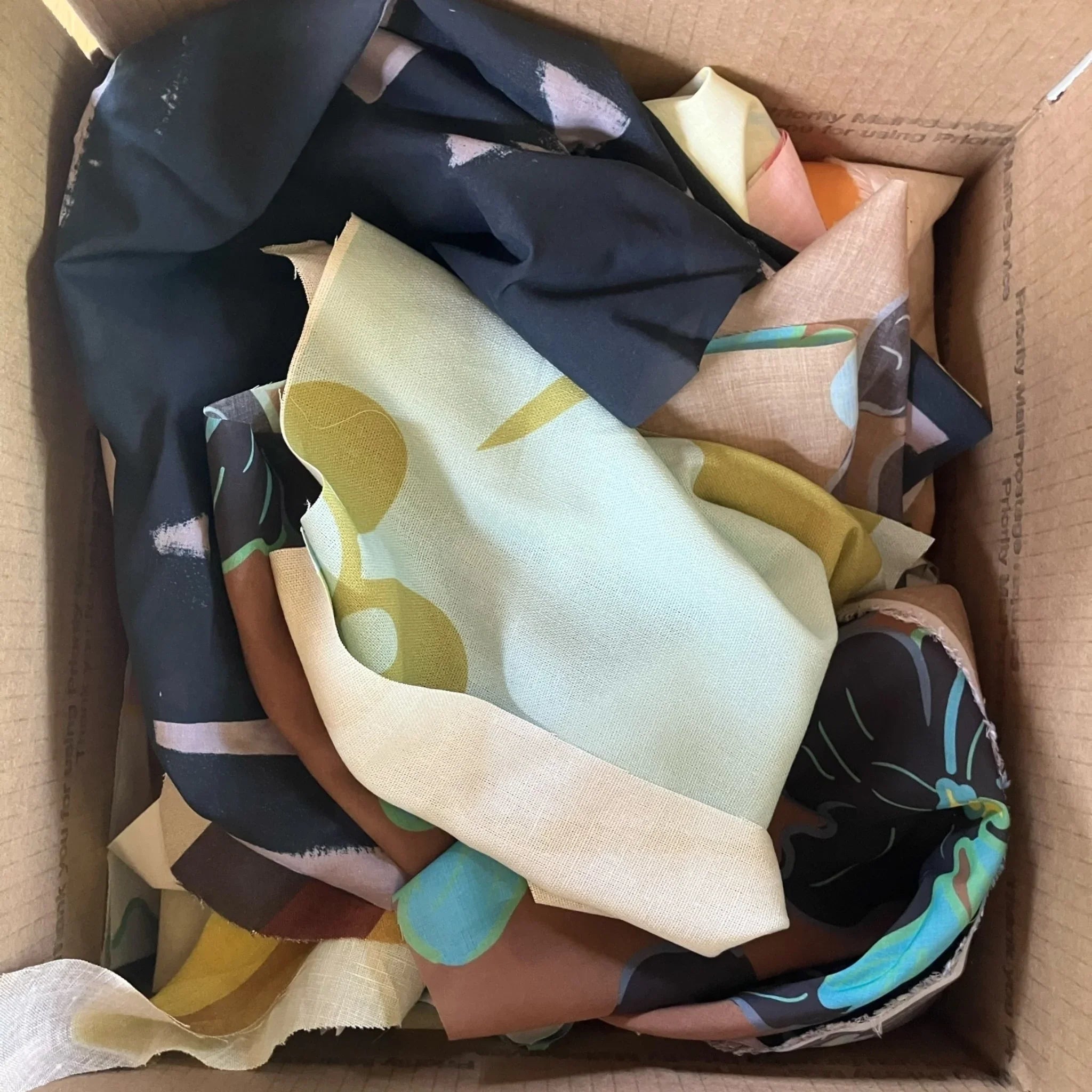 Box of colorful Hawaiian print fabric scraps, featuring modern floral patterns