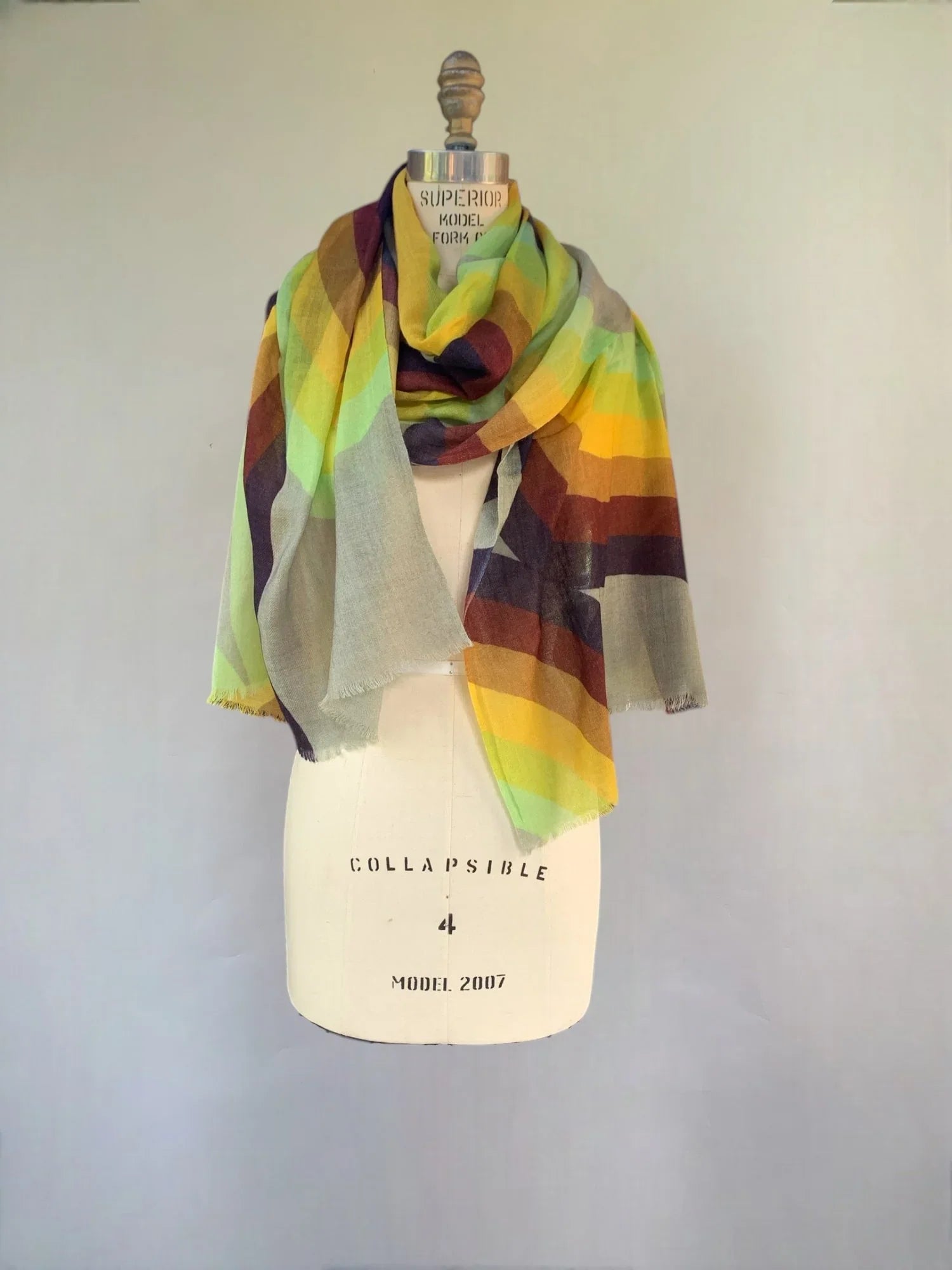 Lightweight scarf with rainbow stripes draped on a dress form against a plain background.