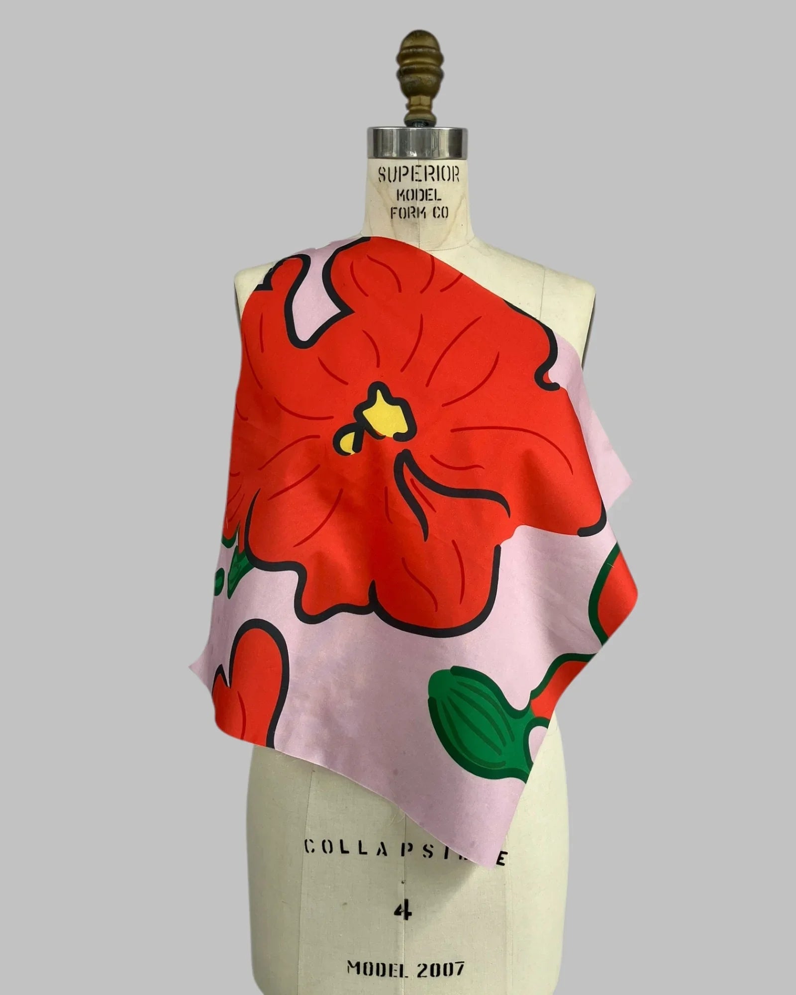 Pink fabric swatch with bold red hibiscus flower and green leaves on dress form