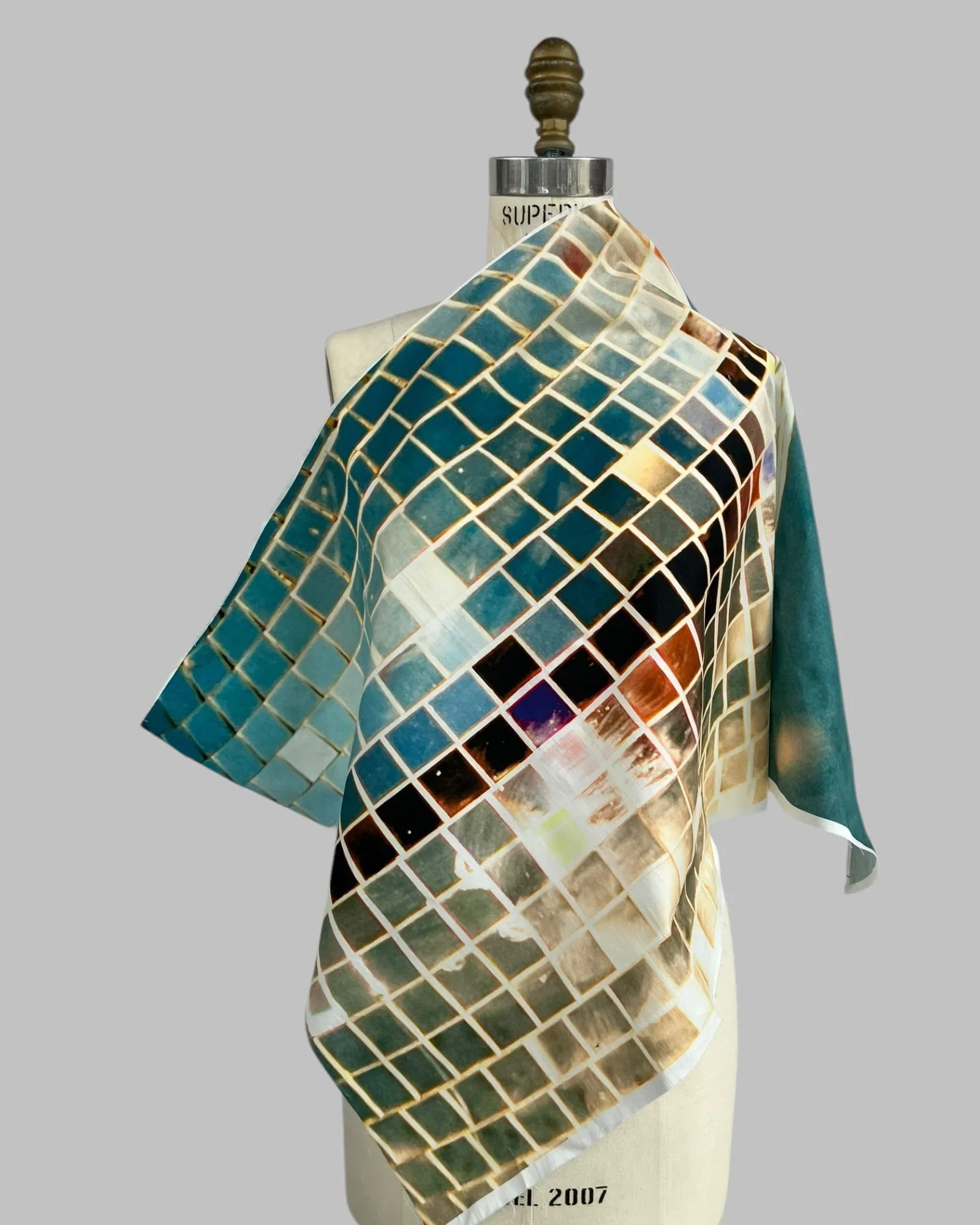 Colorful silk scarf with mosaic tile print draped on dress form, modern wearable art