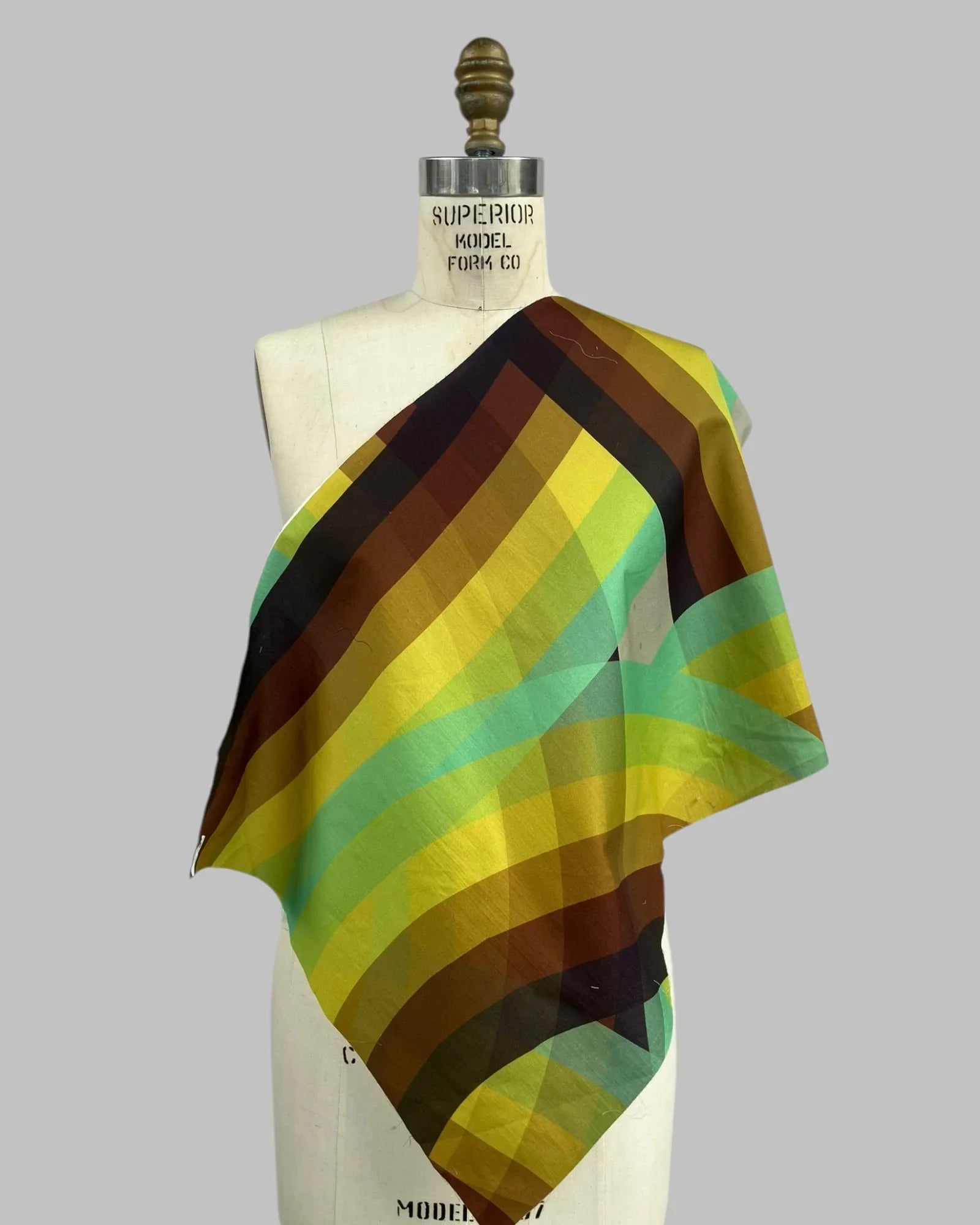Rainbow striped fabric swatch in green, yellow, and brown draped on dress form