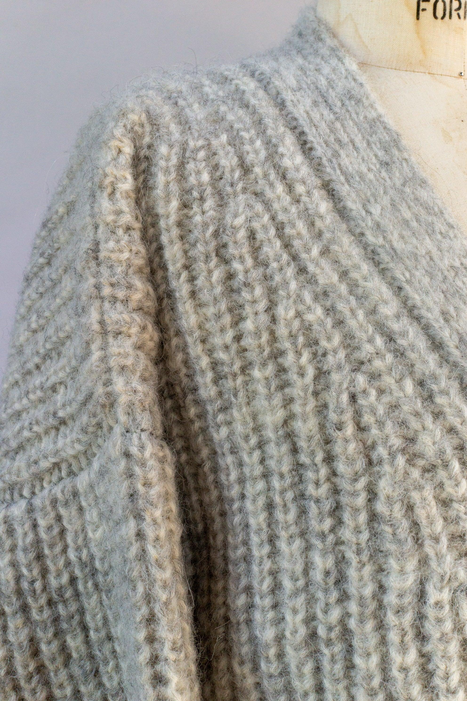 Closeup of a chunky knit grey sweater with ribbed texture on a mannequin