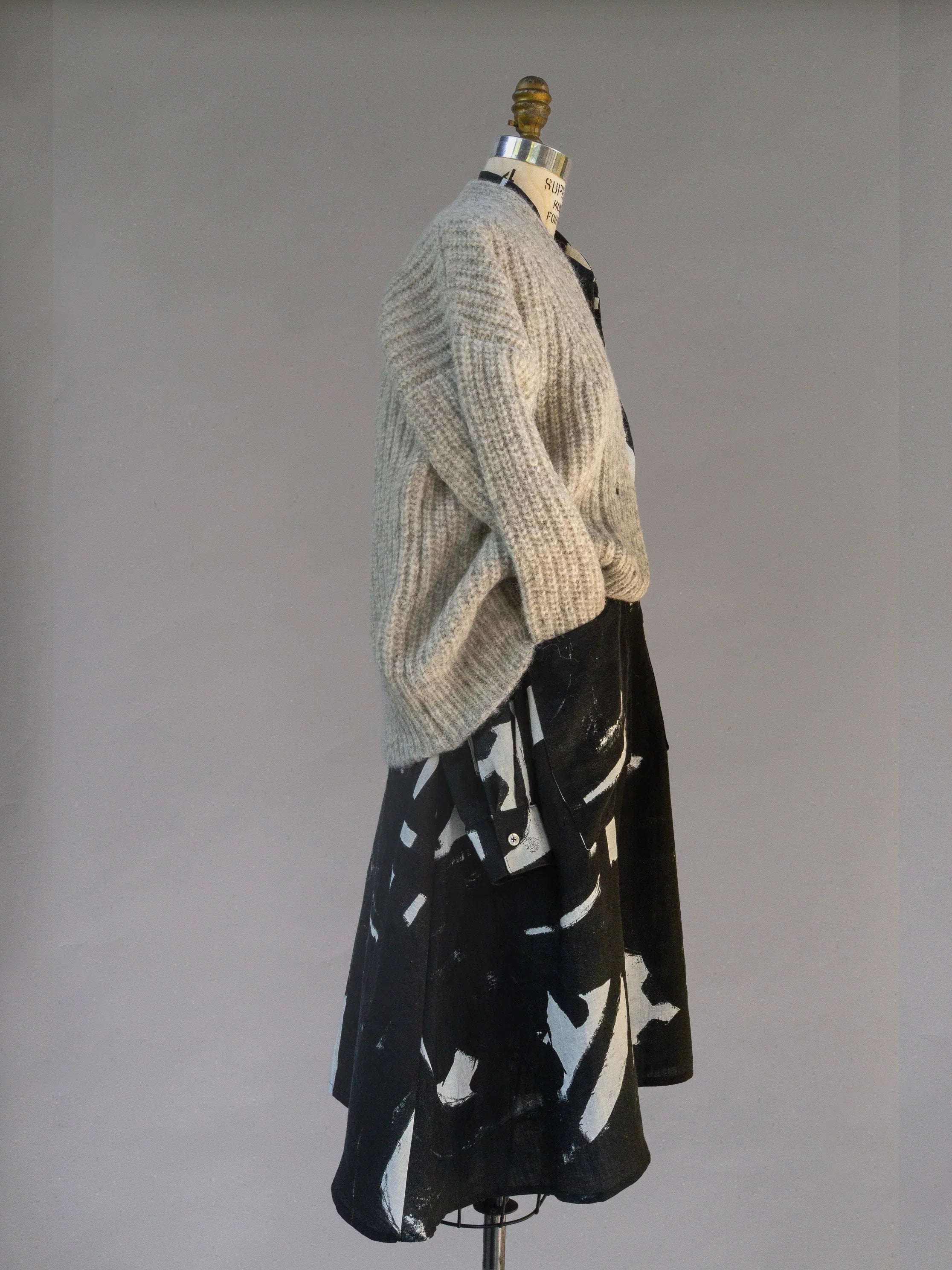 Textured beige sweater over black and white abstract print dress on mannequin