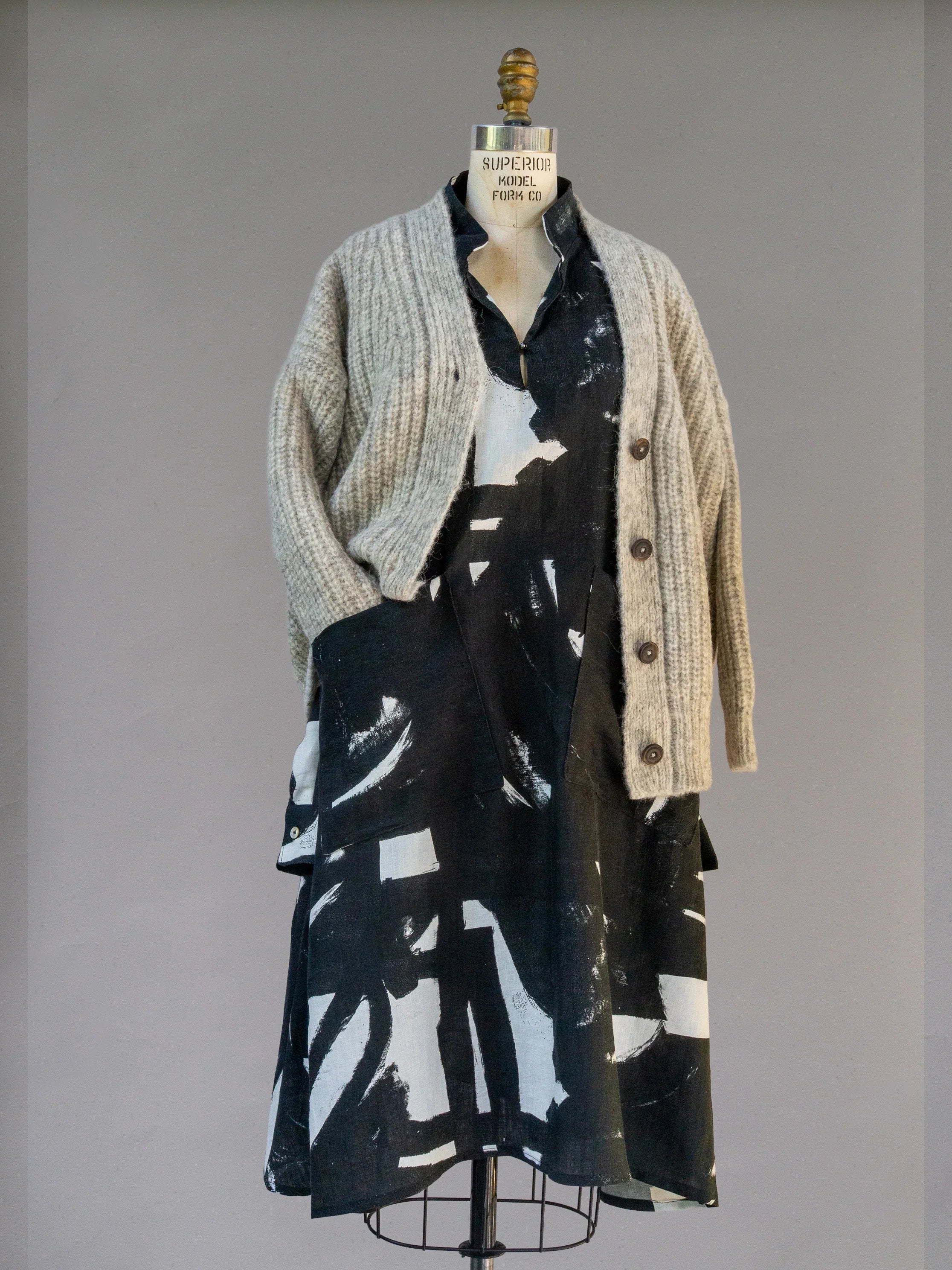 Mannequin wearing a black and white abstract print dress with a chunky grey knit cardigan