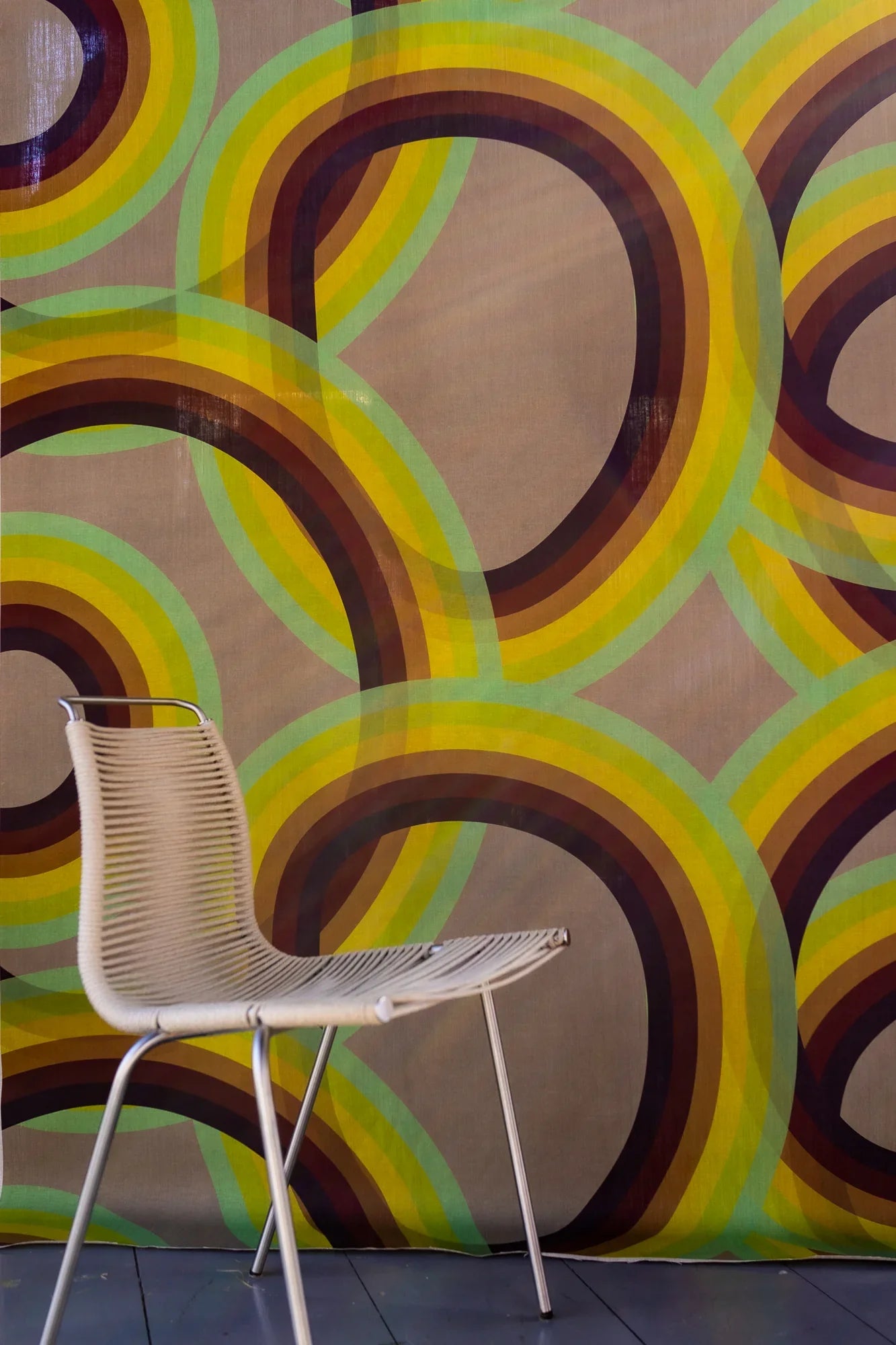 Modern chair in front of retro rainbow Saturn linen wallpaper with overlapping circles.
