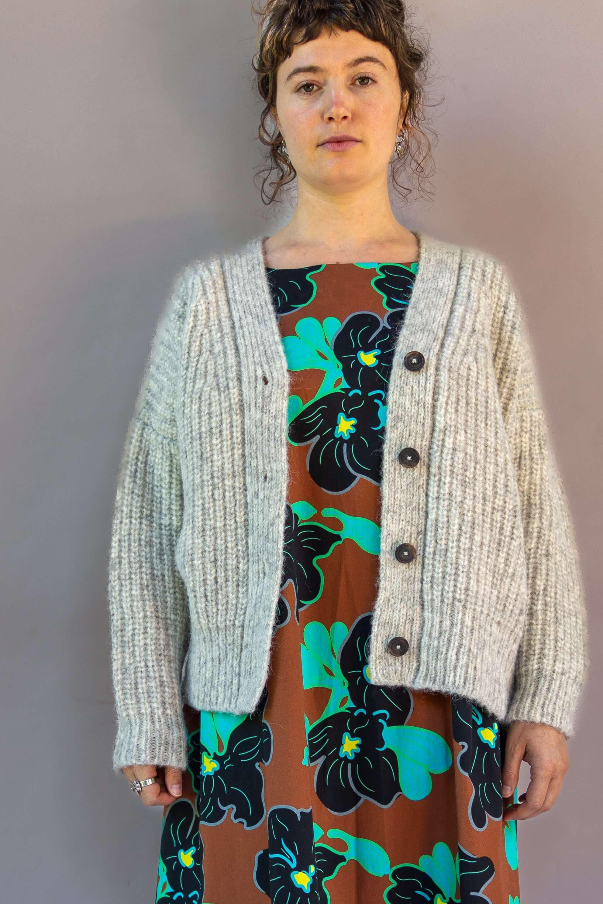 Woman in a black floral print mu'umu'u dress with a chunky knit beige cardigan