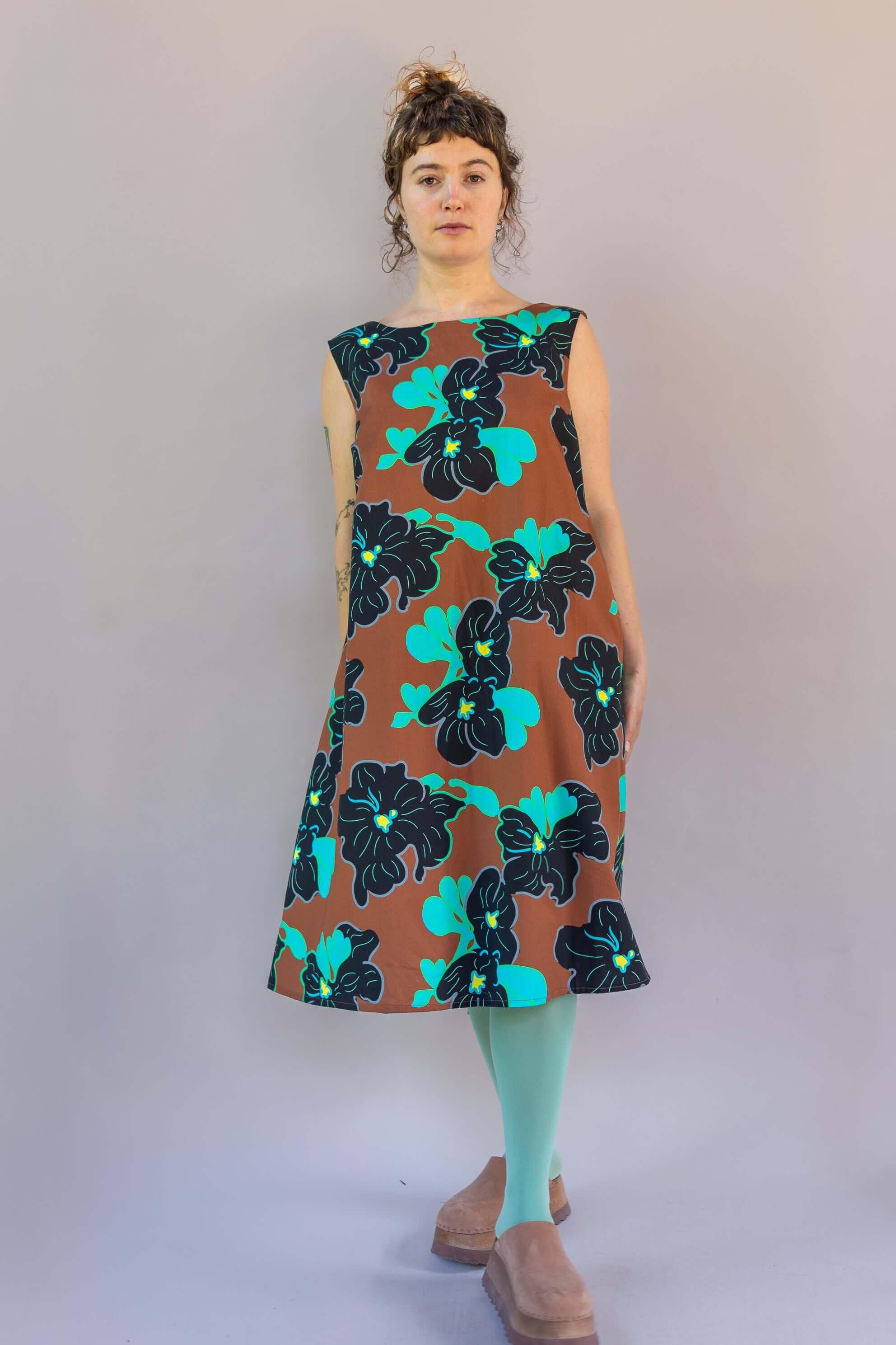 Model wearing the Watteau Dress 1961 Chestnut with vibrant floral print, showcasing its modern design and loose silhouette.