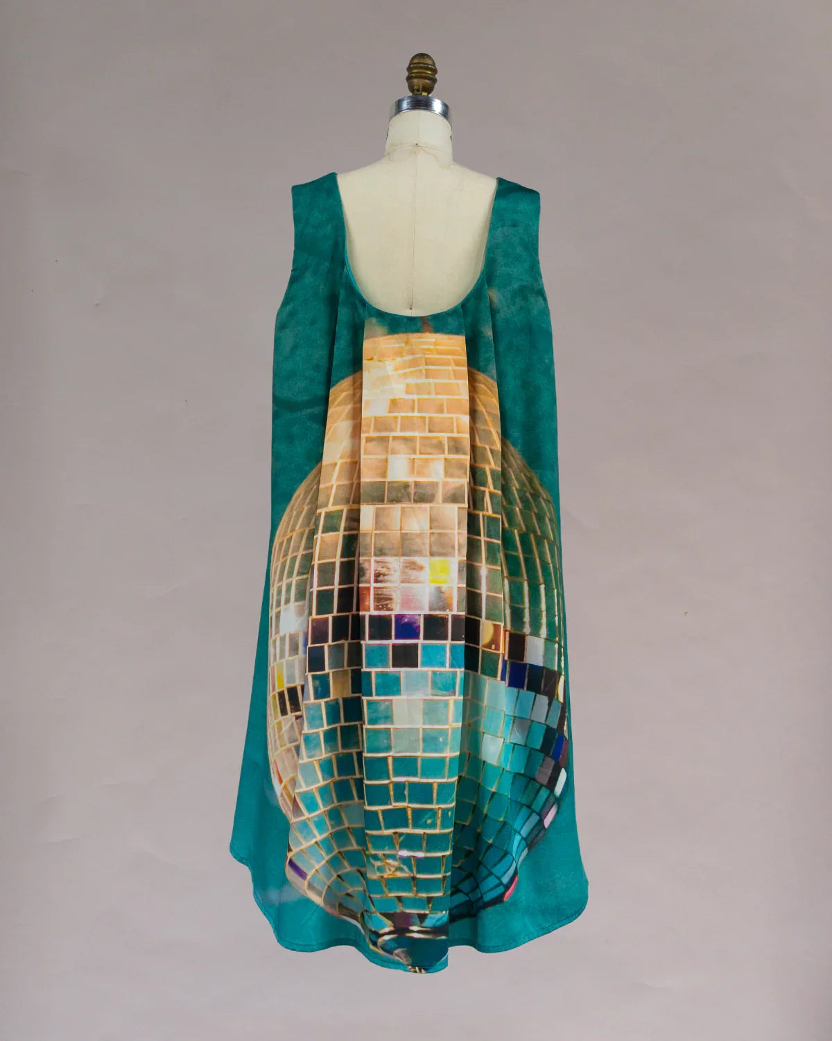 A knee-length cotton dress with a geometric multicolor print, featuring watteau pleating down the back, displayed on a mannequin.