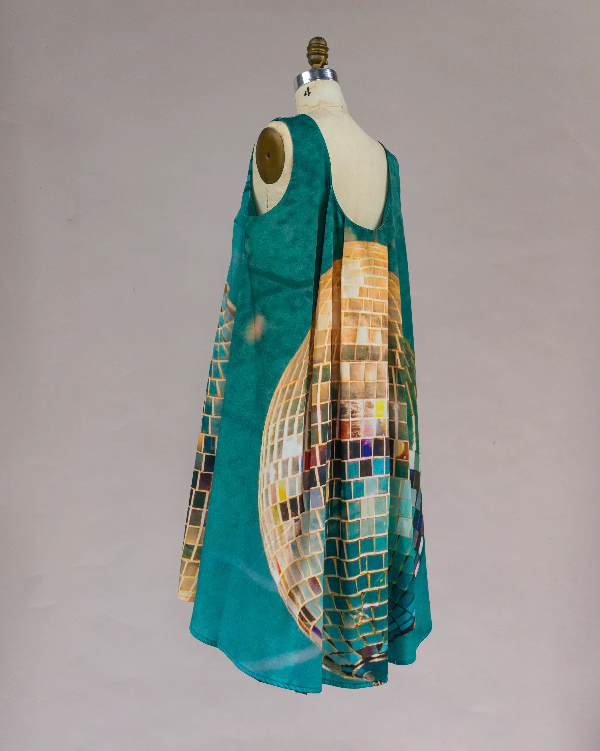 Teal mu'umu'u dress with disco ball print on mannequin, modern Hawaiian fashion