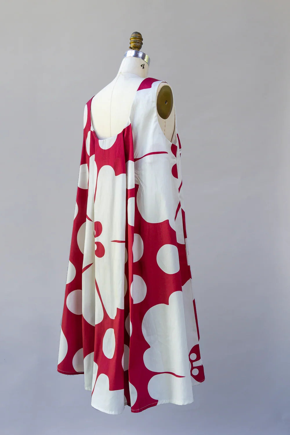 Sleeveless muumuu dress with bold red and white Hawaiian floral print on mannequin