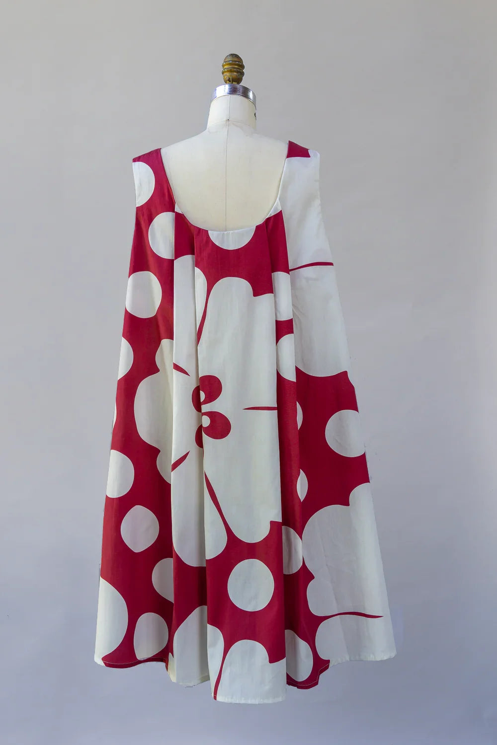 Sleeveless dress with bold red and white Hawaiian floral print on a mannequin