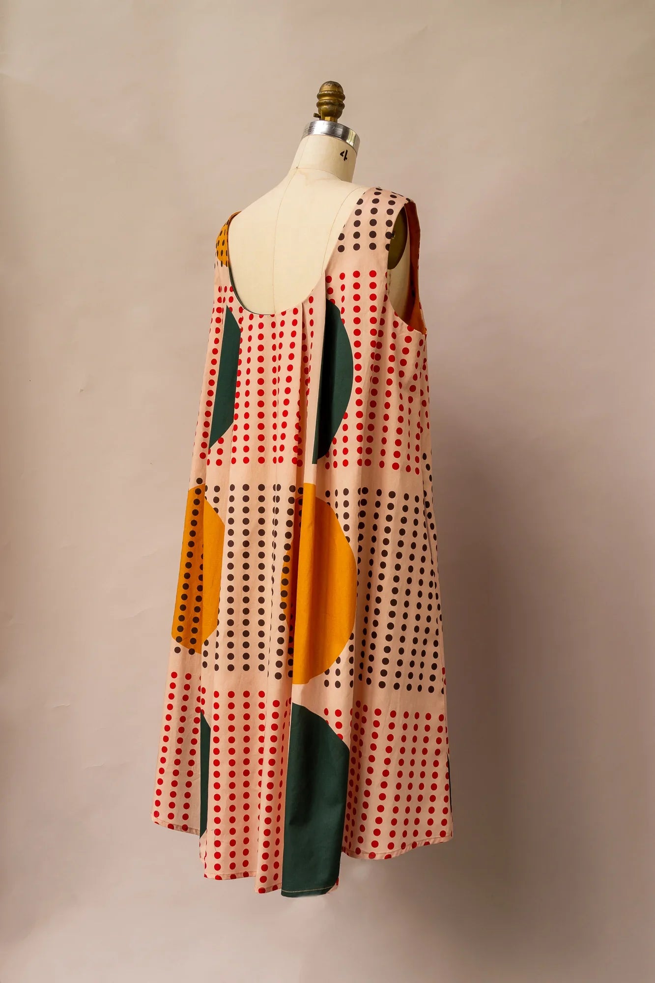 Sleeveless modern muumuu dress with geometric print in red, yellow, and green on mannequin