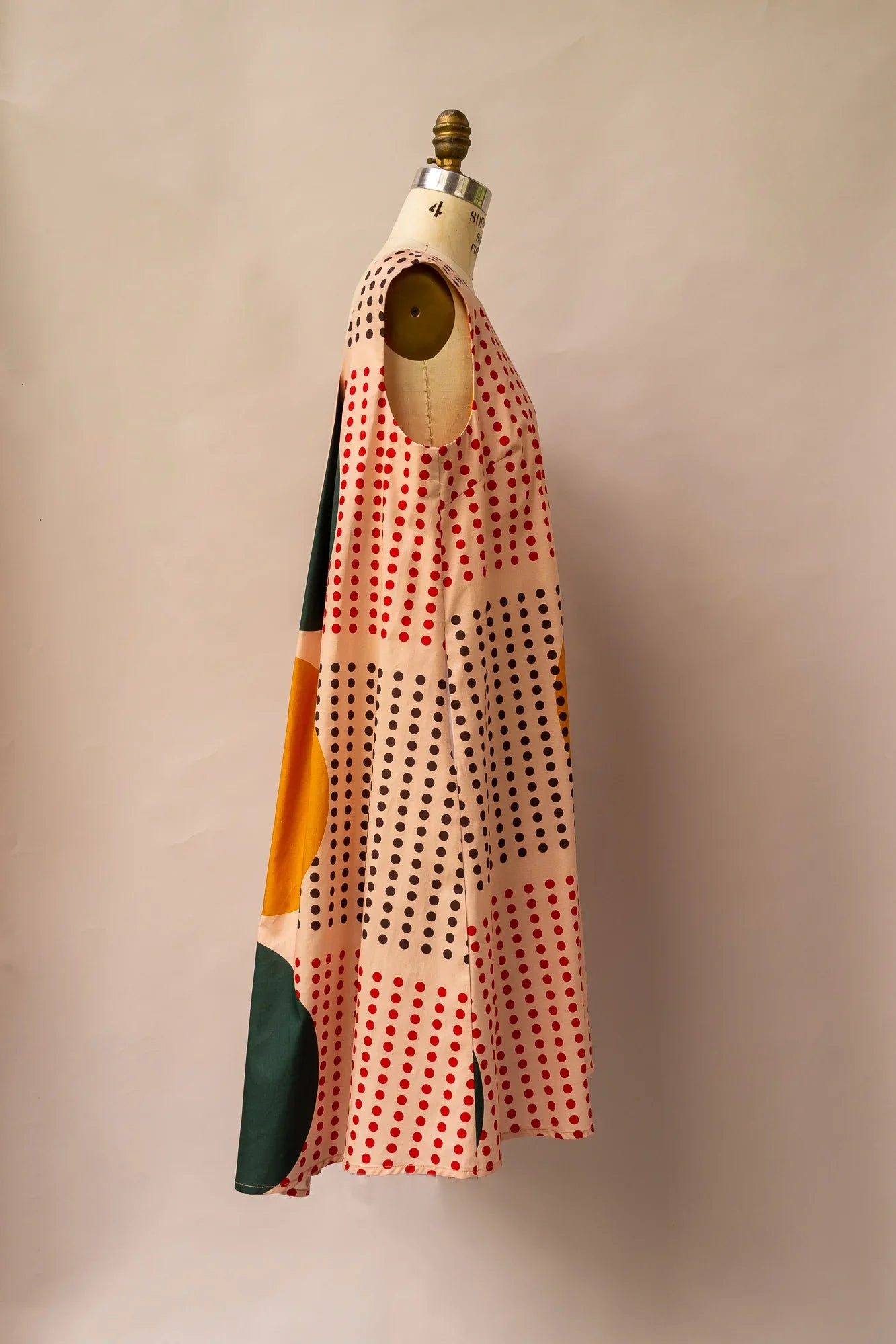 Sleeveless modern muumuu dress with red and black polka dot and abstract print on mannequin