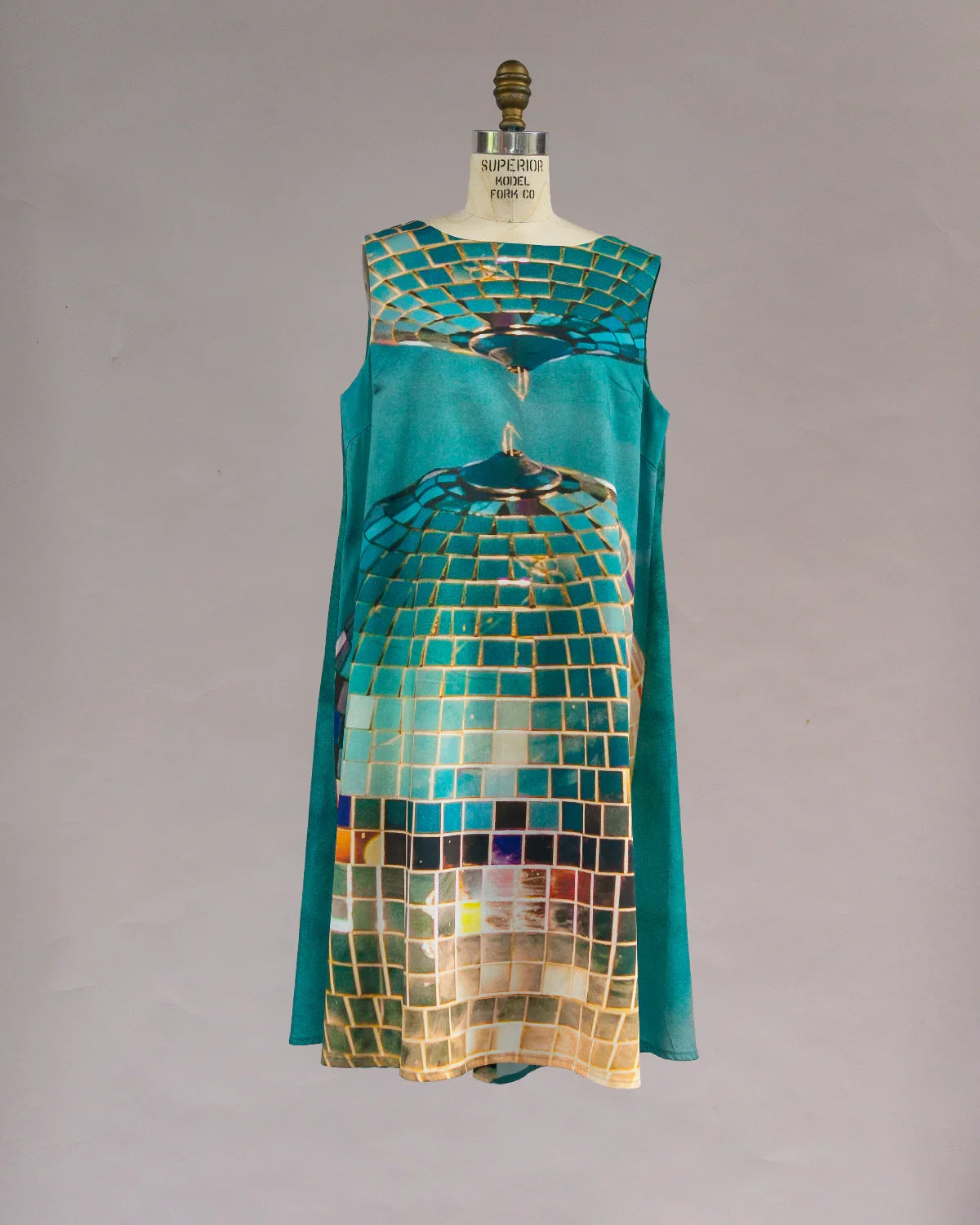 Sleeveless teal muʻumuʻu dress with abstract disco tile print on mannequin