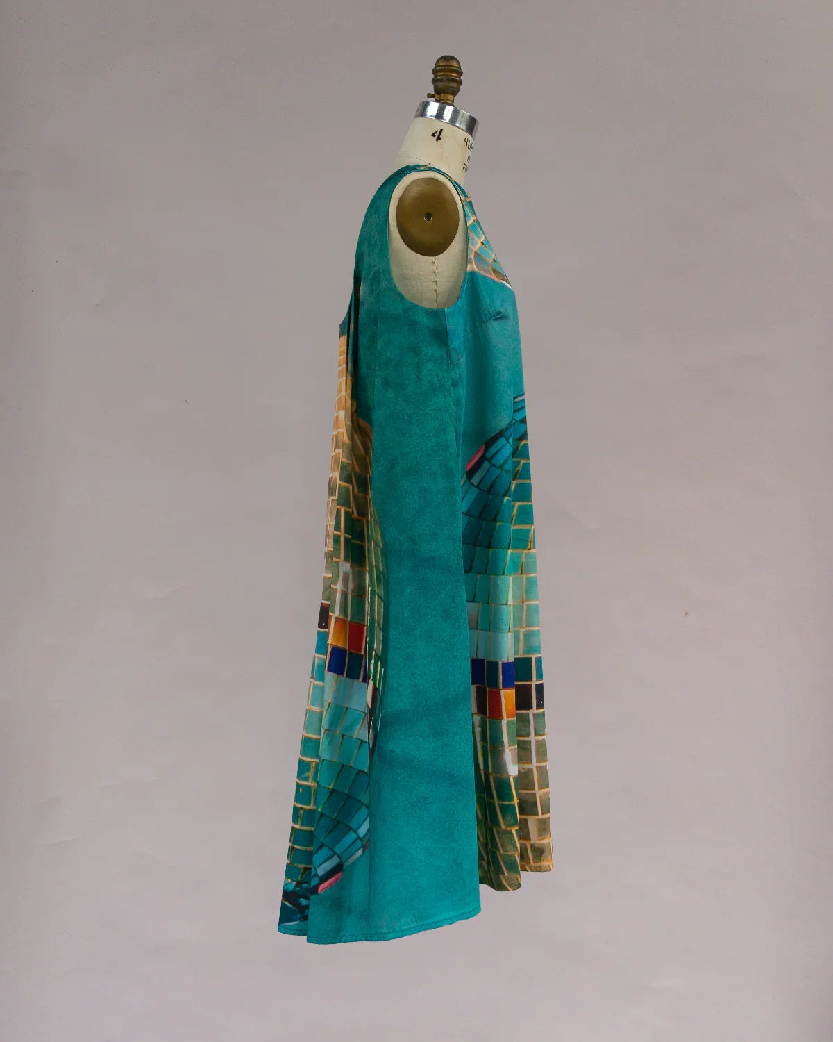 Modern muumuu dress with teal and mosaic tile print on mannequin side view